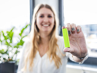 A woman holds a CONCHIFERA battery cell module in her hand and shows it to the camera.