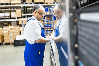 A man stands in front of a machine in the assembly hall for INVENOX battery systems.